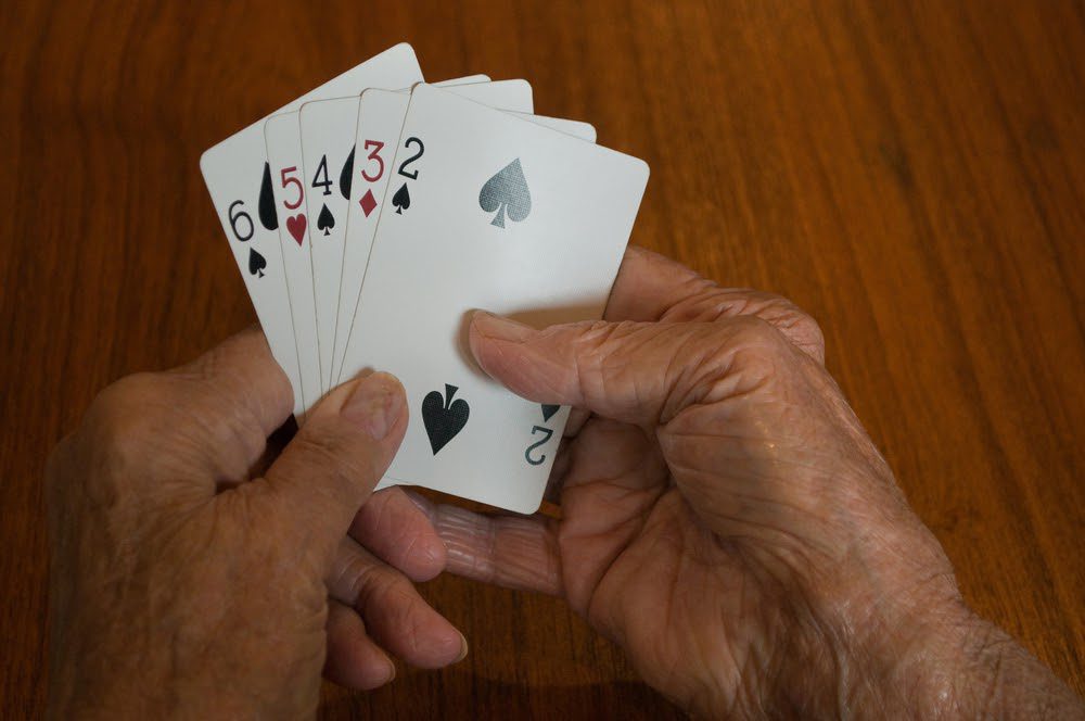 older citizen holding playing cards