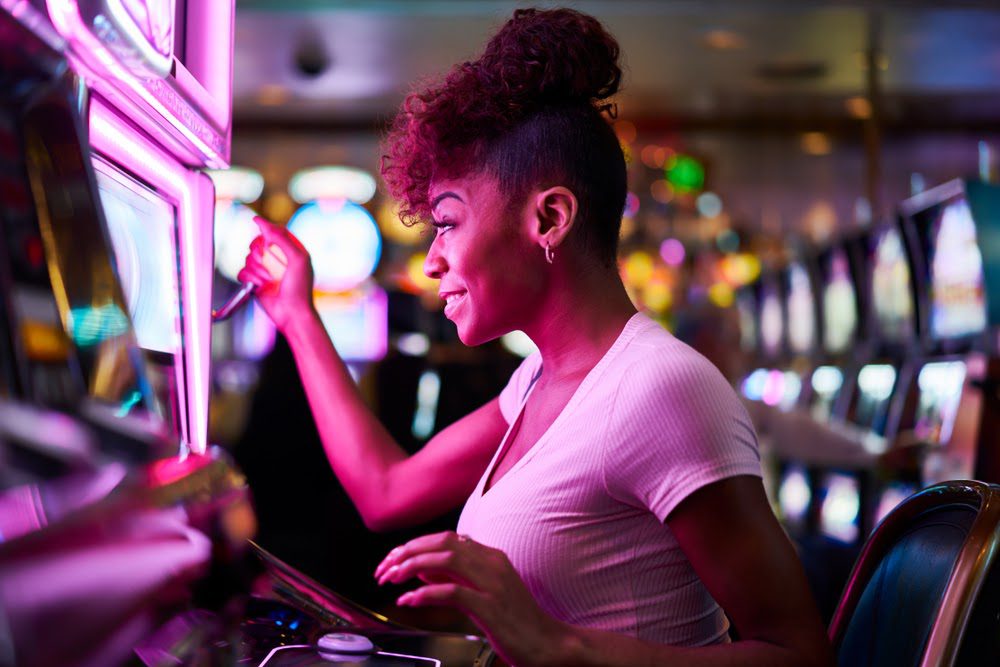 smiling woman playing slot machine in casino