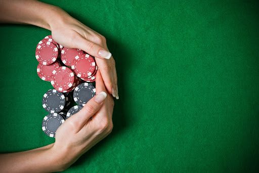 hands around pile of black and red poker chips on green background