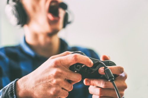 Young man having fun playing video games online using headphones and microphone - Close up male hands gamer holding a joystick - Vintage filter - People, technology, gambling concept