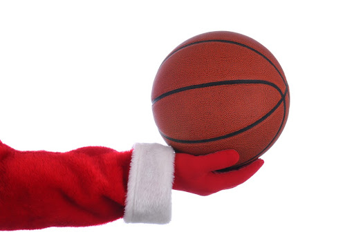 Santa Claus outstretched arm holding a Basketball. Horizontal format over a white background.