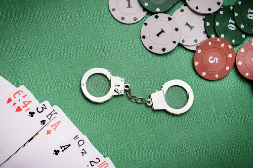 handcuffs on table next to playing cards and poker chips