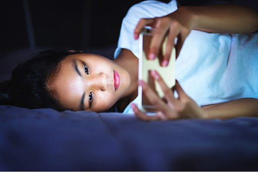 child in bed holding smartphone