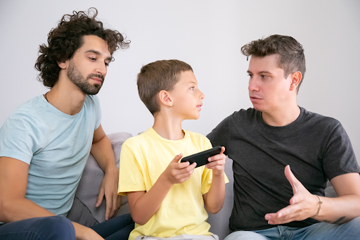 parents talking to child with handheld game
