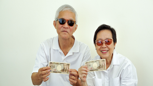 Husband and wife holding up money in front of a white background